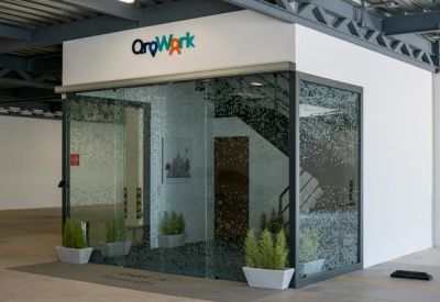 Glass-enclosed office entrance with potted plants and industrial ceilings.