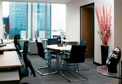 Private office suite with a round meeting table, workstations, and a decorative floral arrangement.