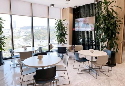 Cafeteria area with white circular tables and indoor potted trees.