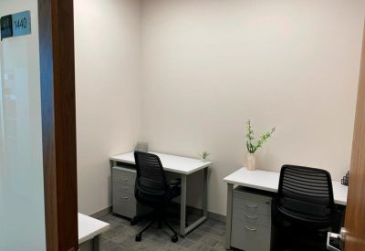 Small private office with two white desks and black mesh chairs.
