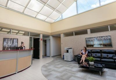 Bright reception area with curved desk, leather sofa, and large skylight.