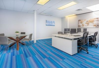 Modern open-plan workspace with vibrant blue patterned carpeting and white desks.
