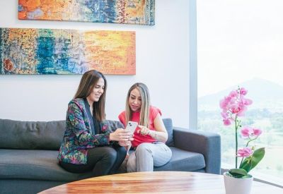 Bright lounge area with two people looking at a phone and pink orchids.
