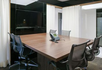 Contemporary meeting room with a wooden table, ergonomic chairs, and a black feature wall.
