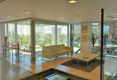 Modern lounge area with leather sofa and large windows overlooking palm trees.