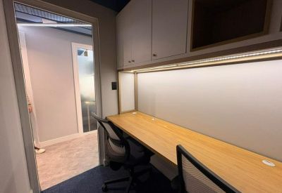 Private office with a light wood built-in desk and white cabinetry.