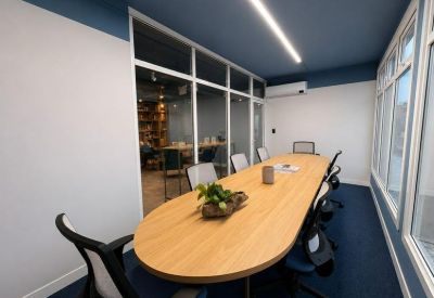 Modern conference room with an oval wood table and glass partition walls.