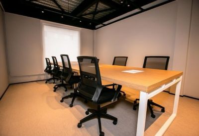 Minimalist meeting room with a large wooden table and ergonomic mesh chairs.