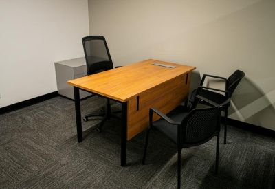 Private office featuring a wooden desk and two guest chairs.