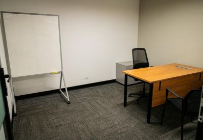 Private office space including a wooden desk and a mobile whiteboard.