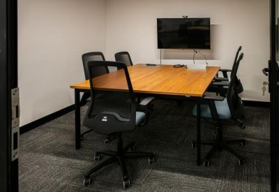 Small meeting room with a wooden table and four mesh chairs.