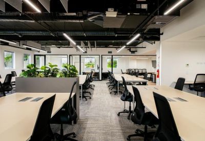 Spacious open office area with black mesh chairs and integrated planters.