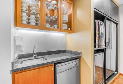 Compact office kitchen with a sink, dishwasher, and wood-finish cabinetry.