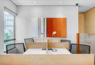 Shared workspace with partitioned desks, mesh chairs, and vibrant orange wall art.