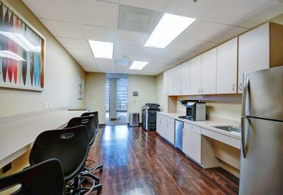 Breakroom with wood floors, long counter seating, and a kitchenette.