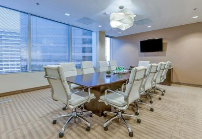 Spacious boardroom with a large wood table, white chairs, and city views.