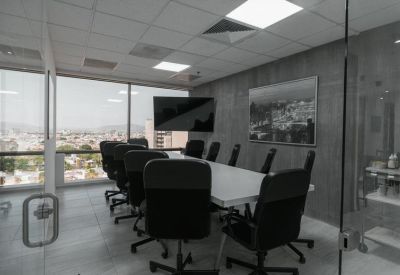 Bright glass-walled boardroom with a large white table and city views.