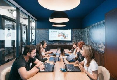 Mood-lit meeting room with people working on laptops under large dome pendant lights.