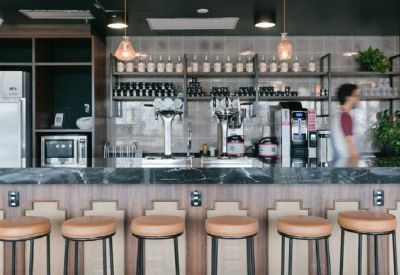 Modern office bar and kitchen area featuring marble counters and professional coffee equipment.