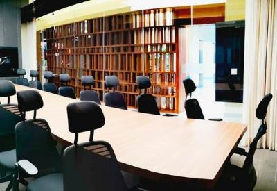 Spacious conference room with an exceptionally long wooden table and numerous black rolling chairs.