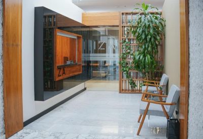 Bright reception area featuring wooden accents, a green potted plant, and stylish grey armchairs.