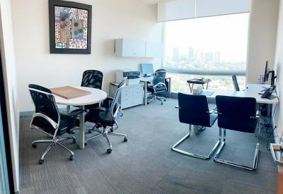 Bright private office suite with multiple workstations, a round meeting table, and large windows.