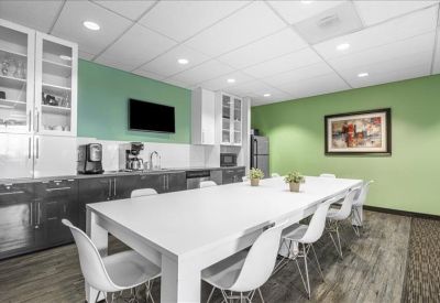 Bright communal kitchen and breakout area with a green feature wall and long white table.