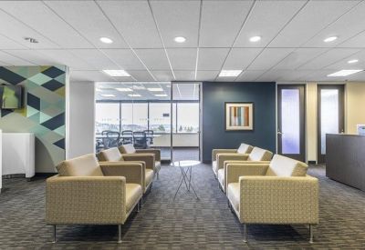 Modern lounge area with comfortable tan armchairs and a dark feature wall.