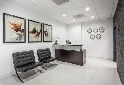 Professional reception area featuring a dark wood desk, guest seating, and world clocks.