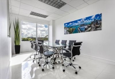 Modern meeting room with glass table, black chairs, and colorful nautical wall art.