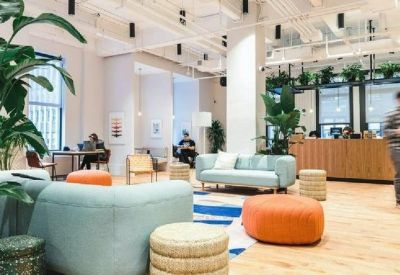 Open-plan coworking area with a wooden service counter and teal lounge seating.