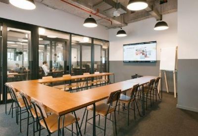 U-shaped conference table in a modern meeting room with glass partitions and a wall-mounted screen.