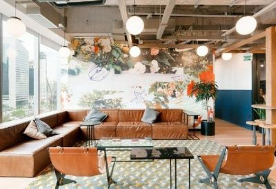 Stylish coworking lounge featuring a leather sectional sofa, colorful wall mural, and globe pendant lighting.