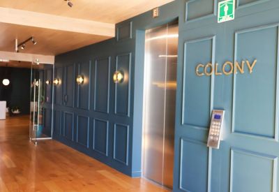 Reception hallway with deep teal panelled walls, wood floors, and gold signage.