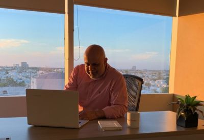 Private office with a sunset city view and a professional at a desk.