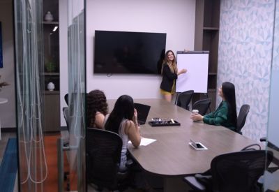 Glass-walled meeting room with a large table, screen, and whiteboard.