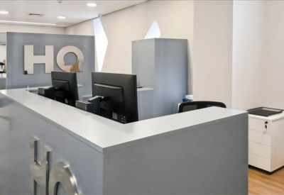 Modern grey reception desk with computer monitors and HQ branding on the wall.