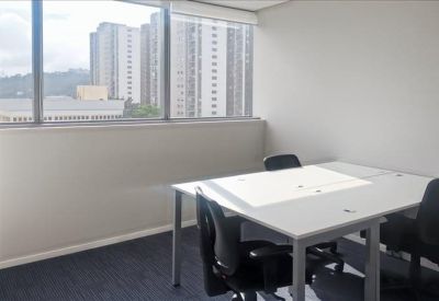 Bright office space with a white desk and views of the city through large windows.