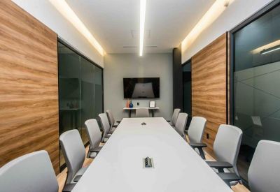 Long white conference table in a meeting room with wood-paneled walls and grey chairs.