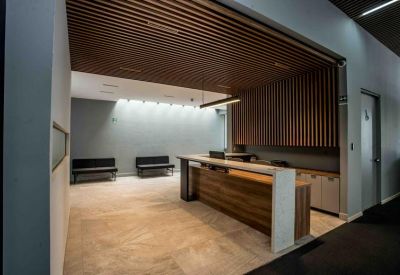 Modern reception desk with wood accents and a slatted timber ceiling feature.
