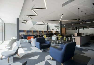 Bright lounge area with blue armchairs, geometric carpet, and decorative pendant lighting.