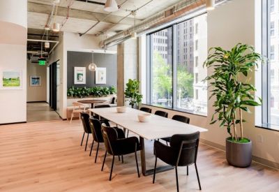 Modern dining area with a long white marble table and black chairs next to a large window.
