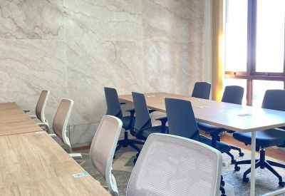 Professional coworking space with long wooden desks and a crystal chandelier.