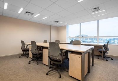 Spacious open-plan office area with several desks and ergonomic chairs.