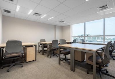 Multiple workstations in a bright office with large windows.