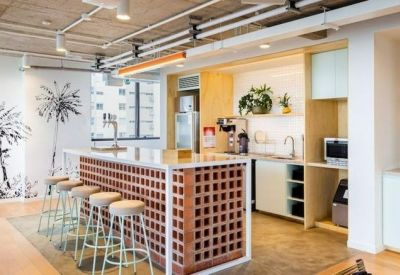Modern kitchen and breakroom featuring a brick-patterned island with bar stools.