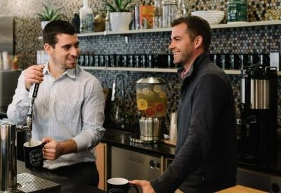Modern office café and coffee bar area with staff and professional espresso equipment.