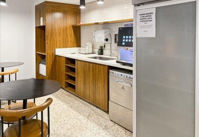 Sleek office kitchenette with a professional coffee machine and wooden cabinetry.