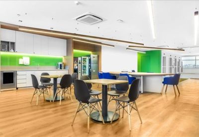 Communal kitchen and dining area with wooden floors and green splashback.