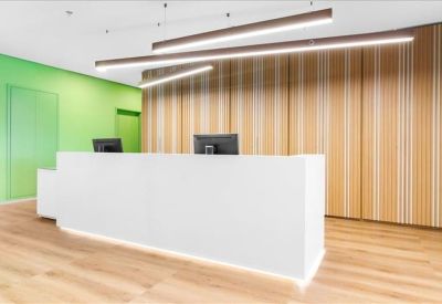 Sleek white reception desk with warm wood paneling and green feature wall.